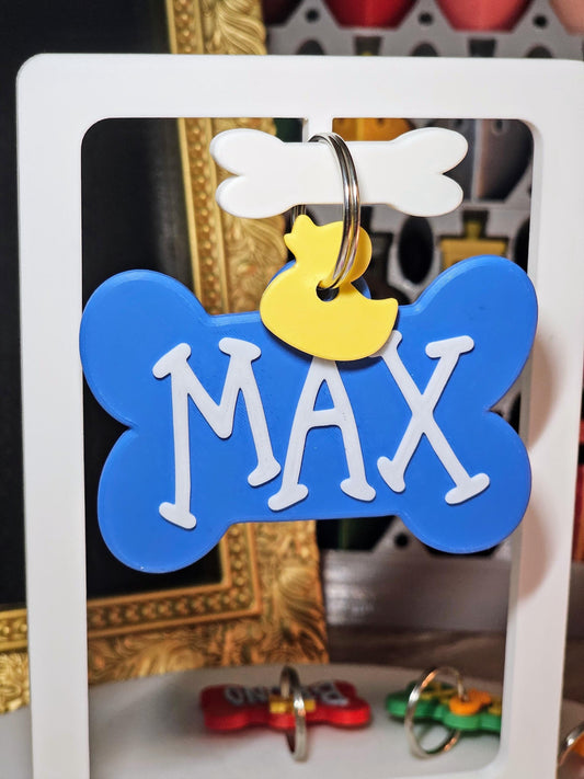 Blue bone tag with the name Max and a duck charm