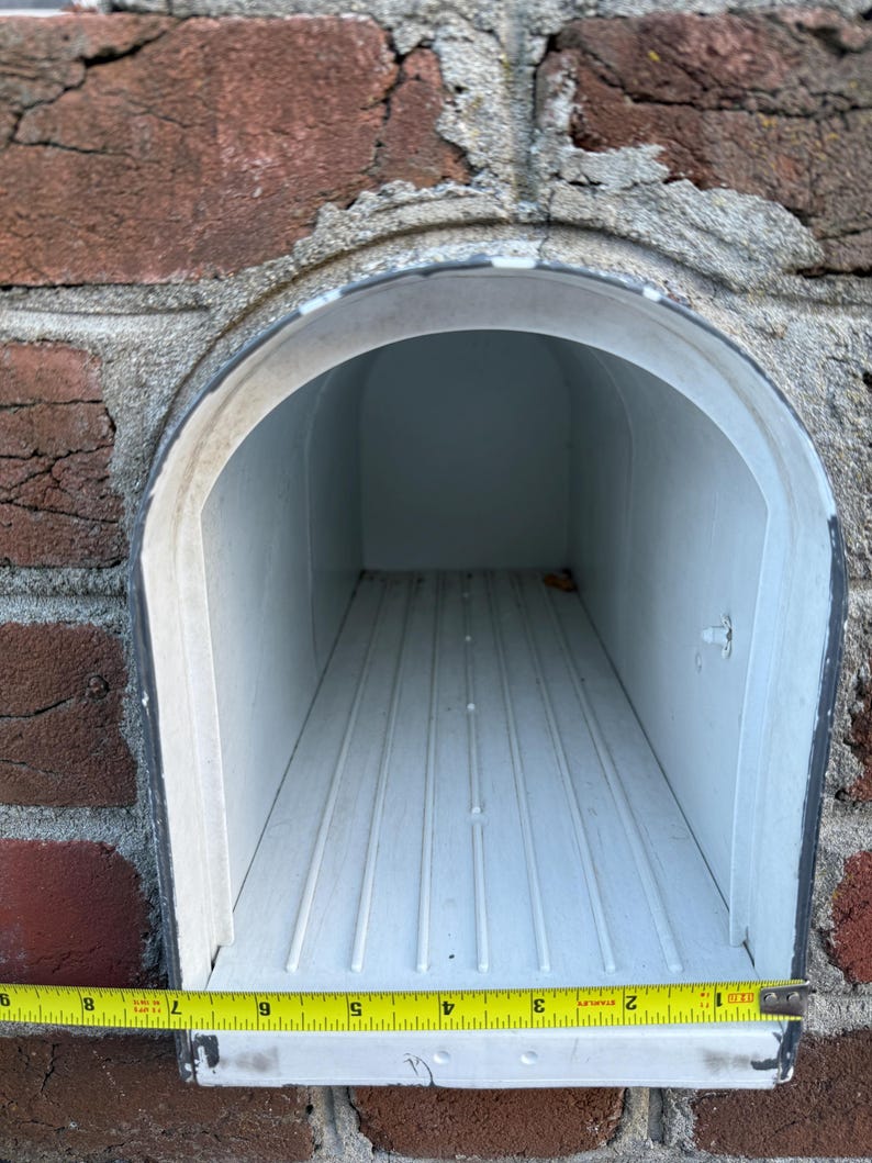 White built-in mailbox opening measuring approximately 9 inches wide