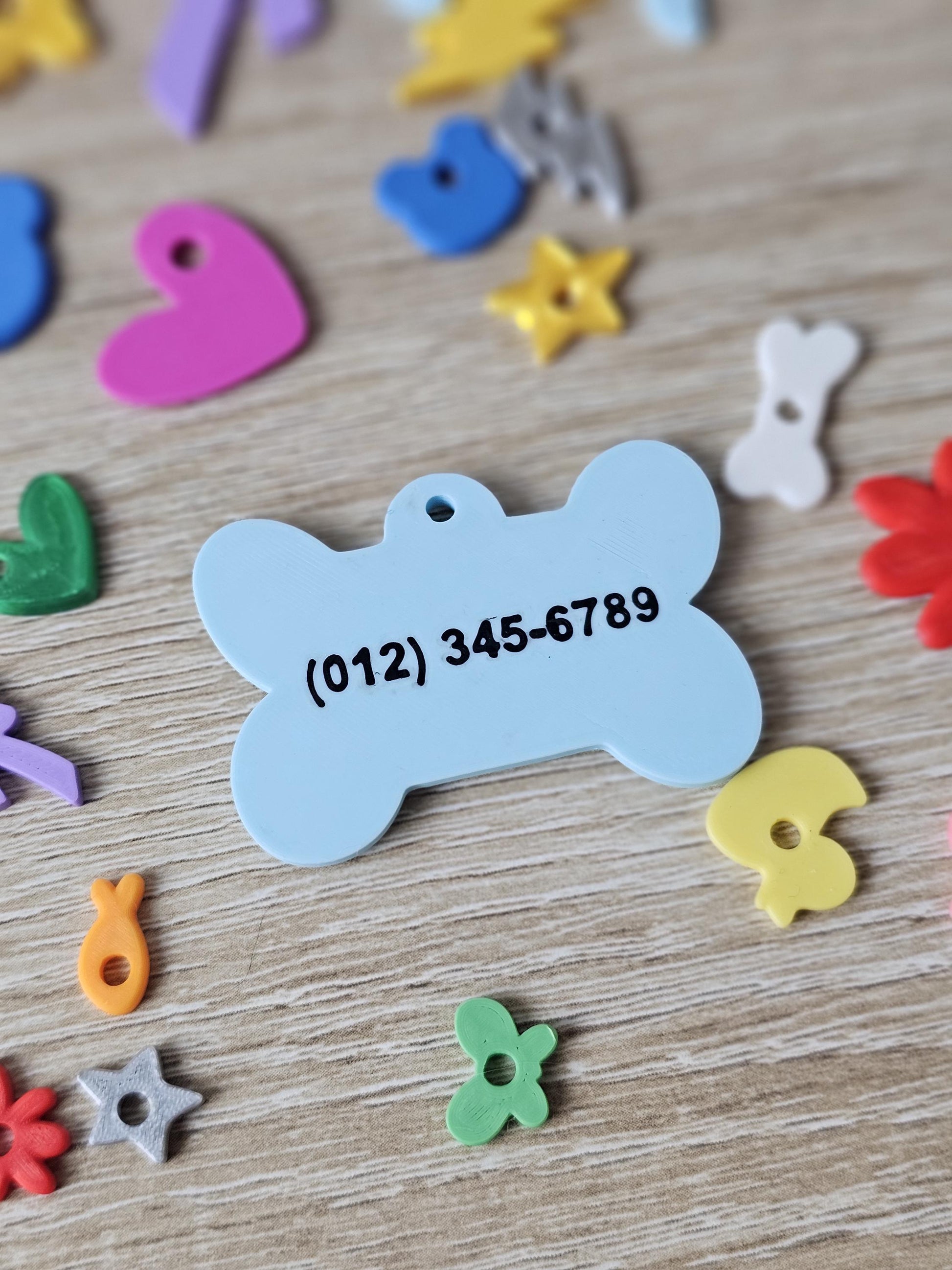 Two-sided bone tag showing a phone number on the back