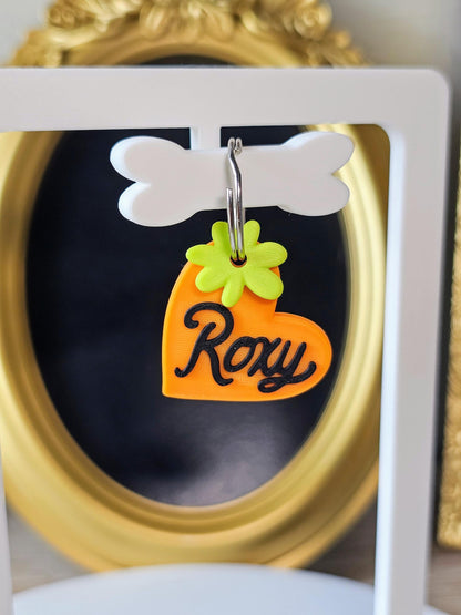 Orange heart tag with the name Roxy and a green flower charm