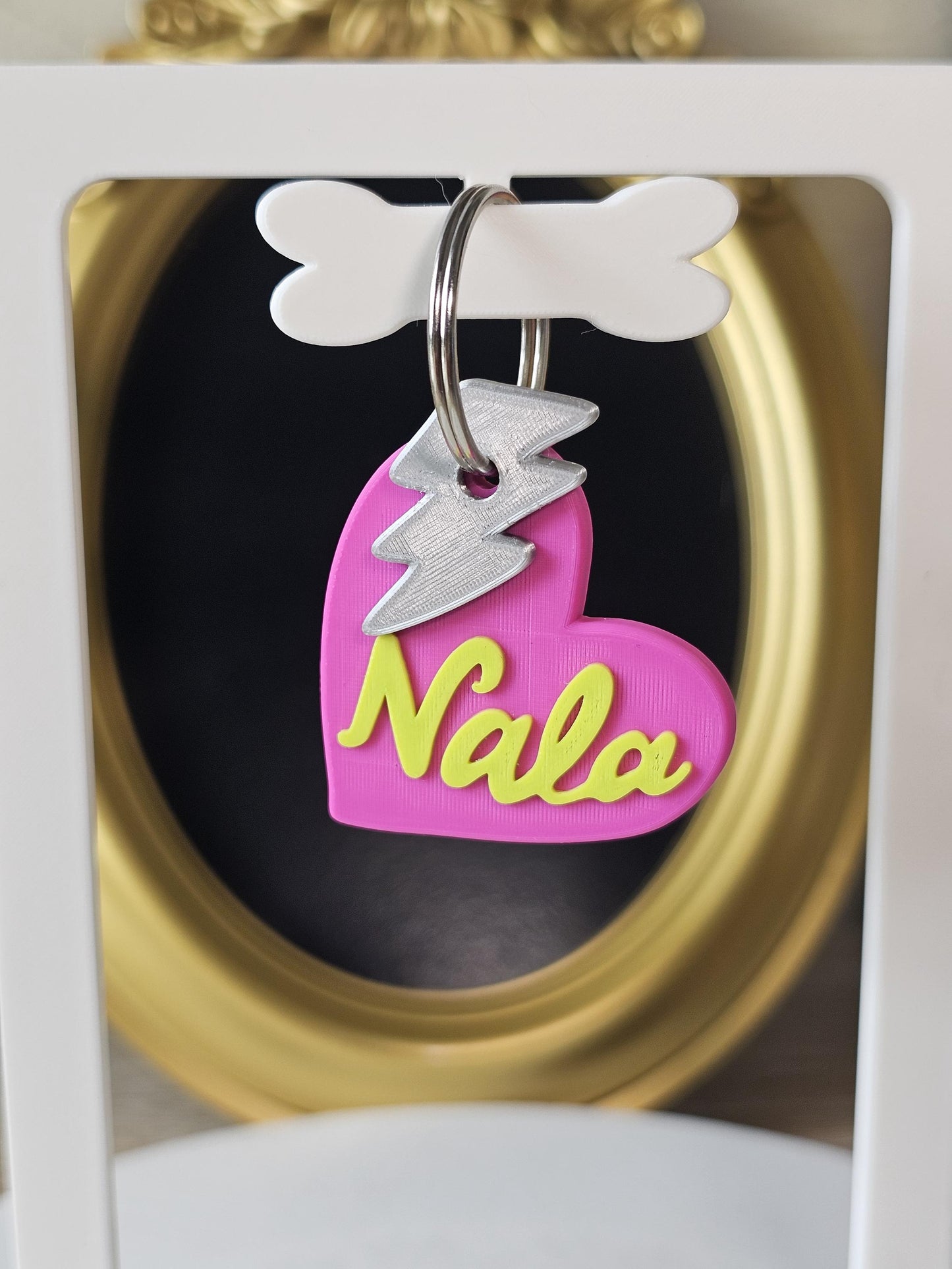 Pink heart tag with the name Nala and a lightning bolt charm