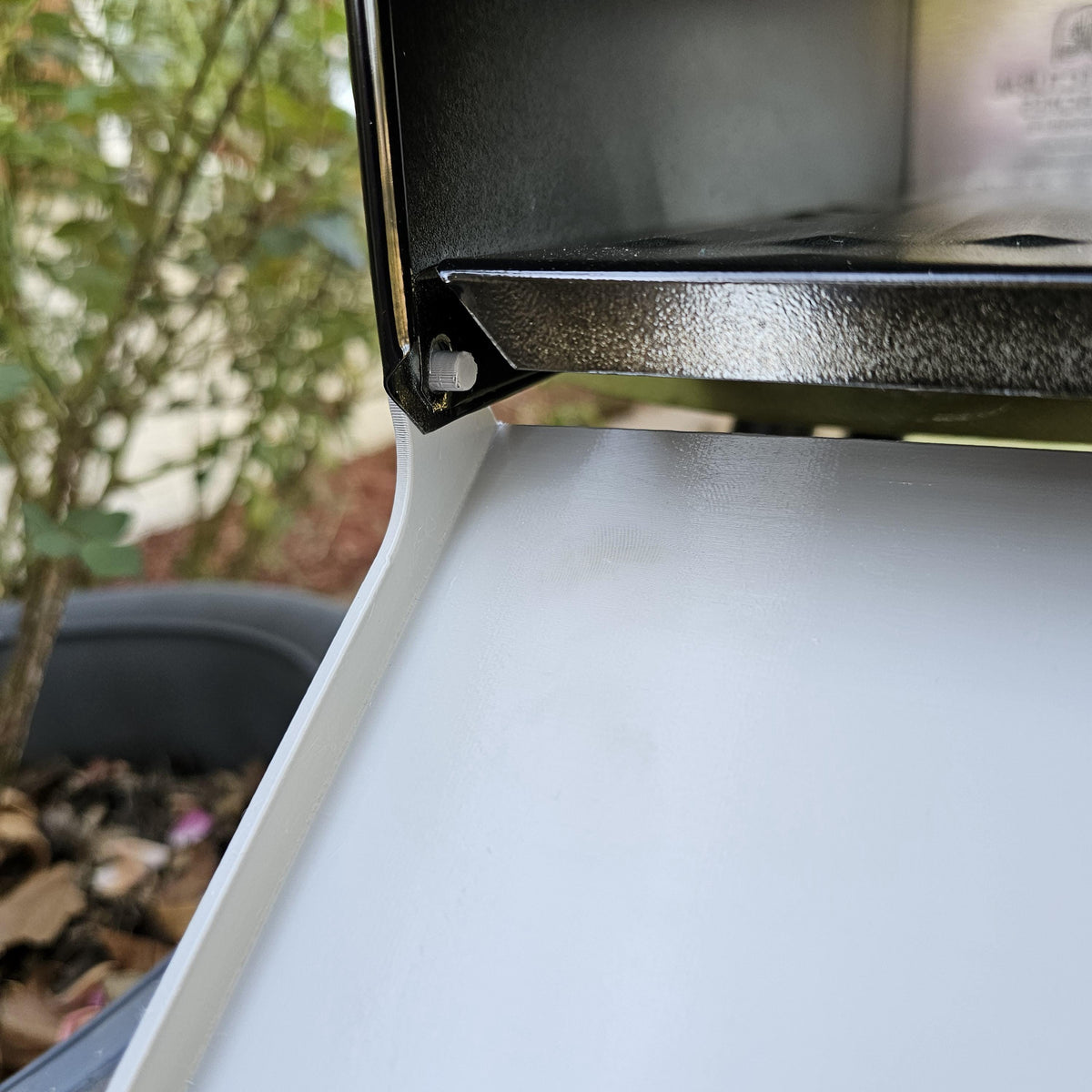 White replacement door open on a metal mailbox, hinge close-up