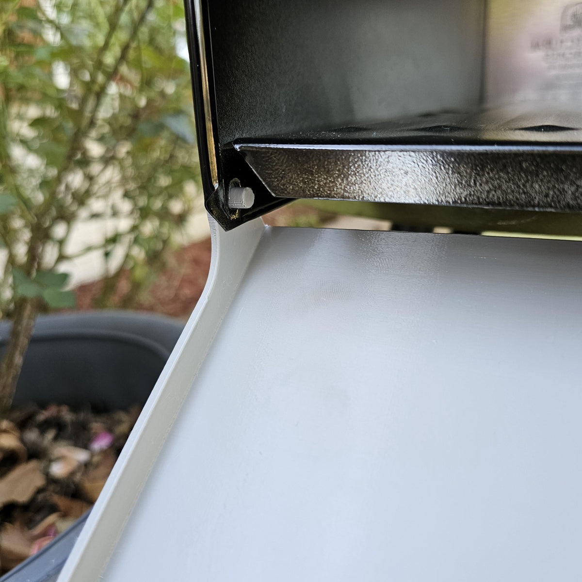 White replacement door open on a metal mailbox, hinge close-up