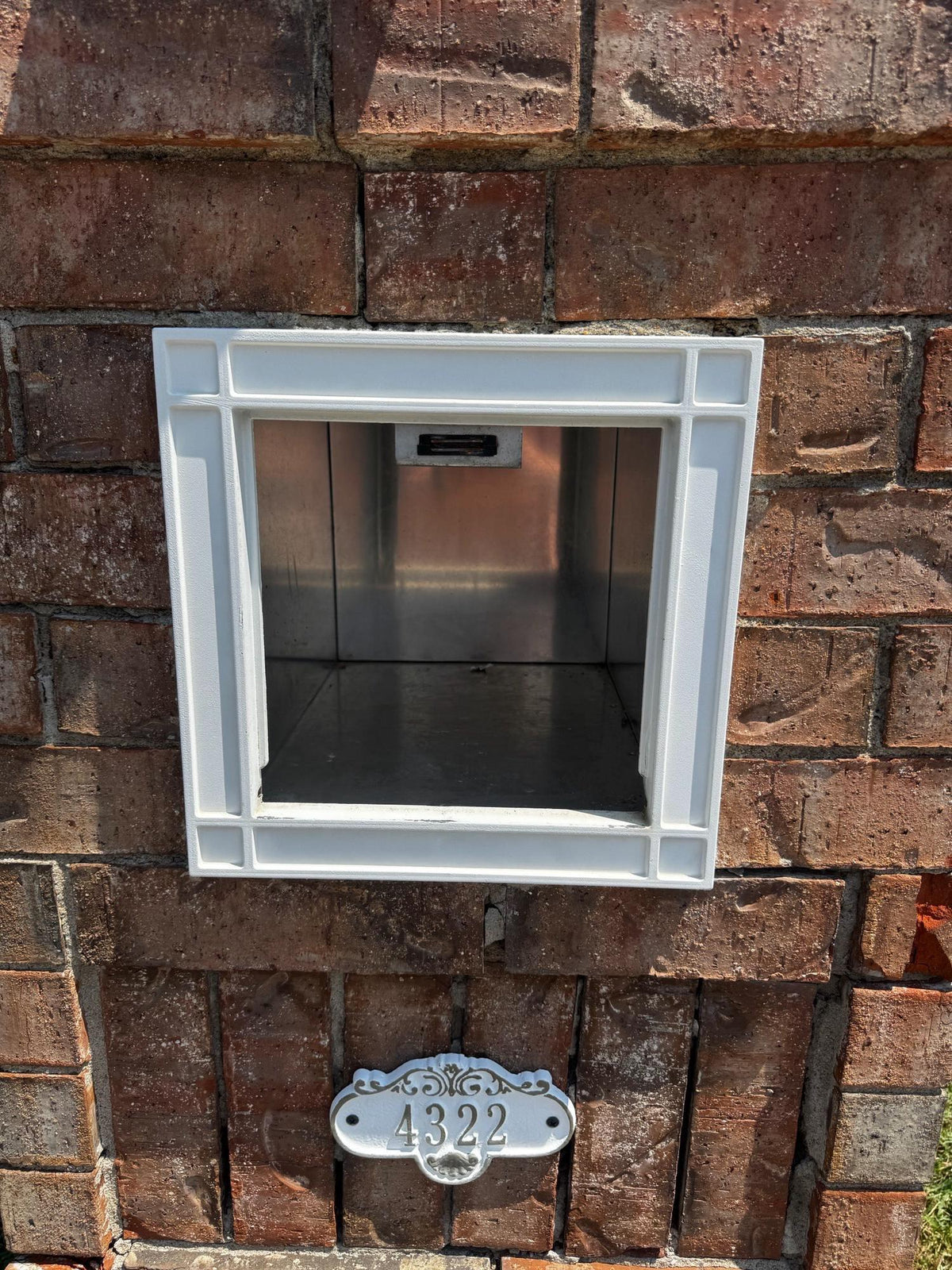 Square mailbox with a white frame set in a brick wall